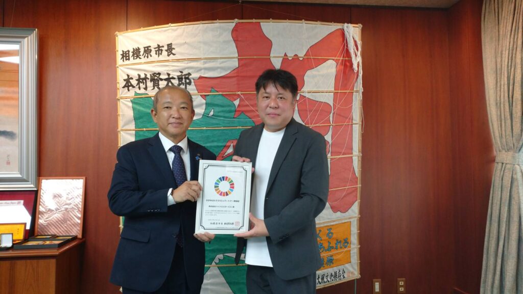 相模原市長の木村健太郎市長と牧野絢一社長のSDGsパートナー登録証を受理した画像